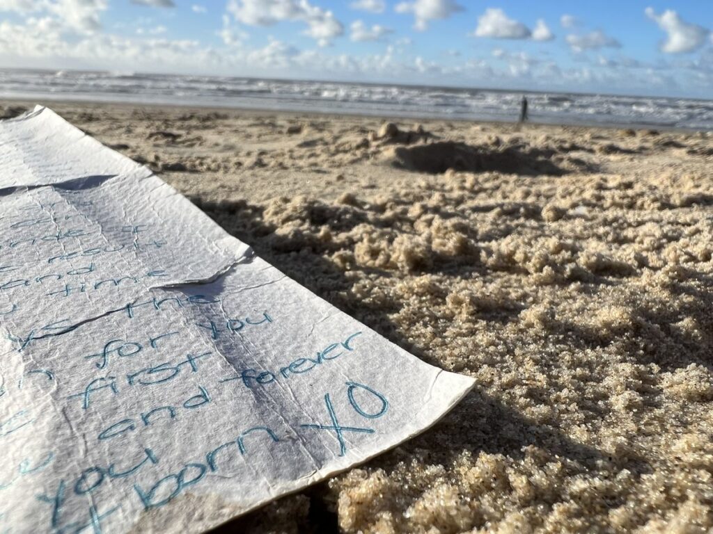 Lettre écrite sur le sable au bord de la mer évoquant une communication marine symbolique